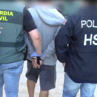 Plano abierto de dos agentes de la Guardia Civil deteniendo un miembro de la organización criminal.