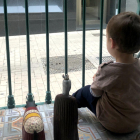 Un nen mira per la finestra de casa, durant el confinament.