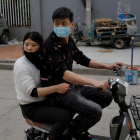 Dues persones que circulen amb moto per un mercat de Pequín, la Xina, porten màscara.