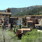 Pla general d'una panoràmica del poble de l'Argentera, al Baix Camp, amb l'església sobresortint d'entre els edificis i, al fons al darrere, molins d'energia eòlica damunt la muntanya