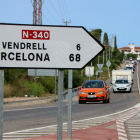 Un letrero de tráfico en primer término a la N-340 en Roda de Berà, con los kilómetros que separan Roda de Berà del Vendrell y Barcelona.
