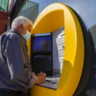 Una persona mayor del barrio de Sant Pere i Sant Pau haciendo gestiones a través de un cajero automático.