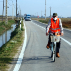 Una persona en bicicleta por la carretera entre el Poble Nou del Delta y Sant Carles de la Ràpita.