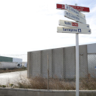Senyals d'indicació al polígon industrial de Valls, amb unes naus en venda al fons.