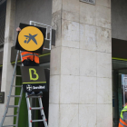 Un operari canviant el logotip de Bankia pel de CaixaBank en una oficina.