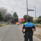 Un agente de la Guardia Urbana de Reus observando el vehículo ardiendo.
