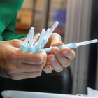 Una operària de planta inspecciona unes mostres de la xeringa que fabriquen per a administrar la vacuna contra el coronavirus.