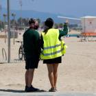 Dos informadores municipales, de espaldas, en la playa del Bogatell.