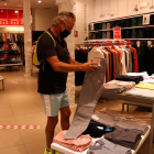Un comprador mirando unos pantalones en una tienda del centro de Reus.