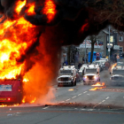 Vehículos policiales detrás de un autobús en llamas en Shankill Road durante las protestas en Belfast.