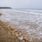Imatge de la platja Llarga, totalment empassada per l'aigua del mar i amb les roques i les saques del mur del càmping caigut.