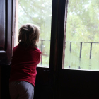 Un niño observa la nieve desde la ventana de su casa.