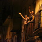Tres joves des d'un balcó del barri de Gràcia celebren que acaba el toc de queda nocturn.
