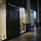 Dues botigues del centre comercial La Maquinista amb la persiana abaixada.
