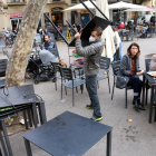 Un treballador d'un restaurant recollint taules i cadires amb gent encara menjant.
