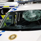 El cotxe patrulla de la Policia Local de Palamós amb el vidre del parabrisa trencat després de rebre l'impacte de dues ampolles.