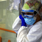 Una infermera vestida amb un EPI en una zona d'UCI amb pacients ingressats a causa de la covid-19.
