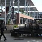 Un chico paseando por al lado de mesas y sillas retiradas en un punto del centro comercial La Maquinista.