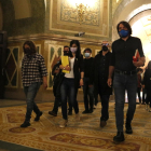 Plano general de los negociadores de ERC, Junts y la CUP caminando por los pasillos del Parlament después de la reunión a tres bandas.