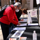 Dues persones signen a favor de la llei d'amnistia, en un acte d'Òmnium a Barcelona.