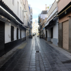Un cèntric carrer de Sitges amb persianes de bars i restaurants abaixades.