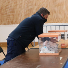 Un operari col·loca les urnes en una mesa electoral del poliesportiu Camp del Ferro de Barcelona.