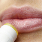 Imagen de archivo de una mujer aplicándose un producto cosmético en los labios.