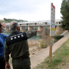 El jefe de los Agents Rurals en el Ebro, Miquel Àngel Garcia, y el biólogo del Grup Natura Freixe, Arnau Pou, señalando los márgenes de la presa de Flix.