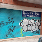Persiana pintada amb graffitis d'un negoci de l'entorn del carrer Santa Joaquima de Vedruna.