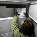 Una trabajadora colocando una caja de vacunas al congelador.