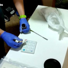 Una mà analitzant la droga intervinguda pels Mossos d'Esquadra.