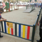 Dos voluntaris de Protecció Civil de Salt posant una cinta en un parc infantil.