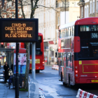 Un bus de Londres passa pel costat d'un cartell que alerta de l'alta incidència de la covid-19 a la capital britànica