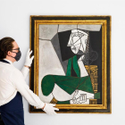 Fotografía cedida por Sotheby's de uno de sus empleados mientras cuelga la obra 'Femme assise en costume vert'.
