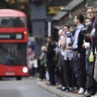 Treballadors esperen en una parada d'autobús de Londres.