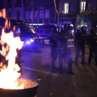 Agentes de los Mossos d'Esquadra junto a una papelera en llamas durante los disturbios posteriores a una manifestación de los CDR por el cuarto cumpleaños del 1-O.