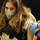 Imatge on es veu com posen una vacuna contra la covid-19 a una noia.