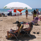 Plano medio de dos personas bajo un parasol en la playa de Salou.