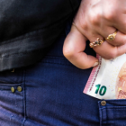 Imatge d'arxiu d'una persona ficant-es diners a la butxaca.
