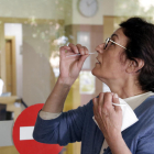 Una mujer haciéndose un frotis nasal para la PCR.