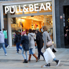Compradors passen per davant d'una botiga Pull & Bear a Barcelona.