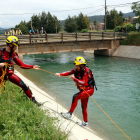 Dos bomberos haciendo prácticas de rescate acuático en el canal de Gavet. Un bombero estira con una cuerda a otro que simulaba haber caído.