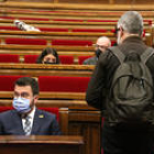 El presidente del Gobierno, Pere Aragonès, y el diputado de la CUP Carles Riera, antes de empezar un pleno en el Parlamento.