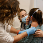 Una enfermera poniendo la tirita a una niña después de ponerle la vacuna.