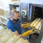 Noel Urbano, de la Pastisseria Noel, ubicada en la calle de Florenci Vives, poniendo en el horno unas barras de pan.