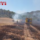 Una dotación de los Bomberos remoja uno de los campos calcinados en el incendio de Sant Jaume dels Domenys.