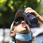 Iatge de archivo de un joven bebiendo agua en la calle.