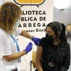 Una infermera posant una vacuna contra la covid-19 a una noia.