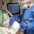 Una profesional sanitaria del Hospital Clínic coge la mano de un paciente ingresado al área de Cuidados intensivos, durante la quinta oleada de la pandemia de la covid-19 en Cataluña.