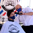 Pla tancat d'un perruquer eixugant el cabell d'una dona que ha participat en la cinquena edició de la campanya “Deixa't prendre el pèl” a Cambrils.